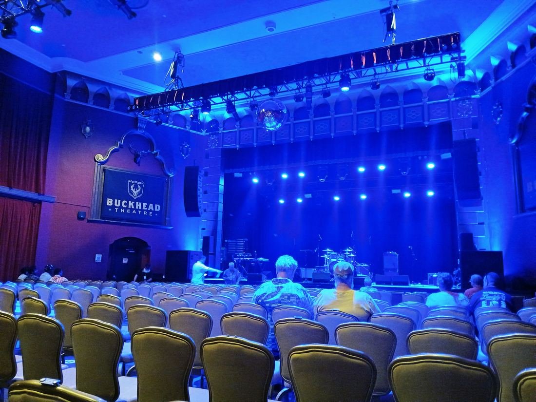 Inside the Buckhead Theatre, with rows of seats facing a stage washed in blue light
