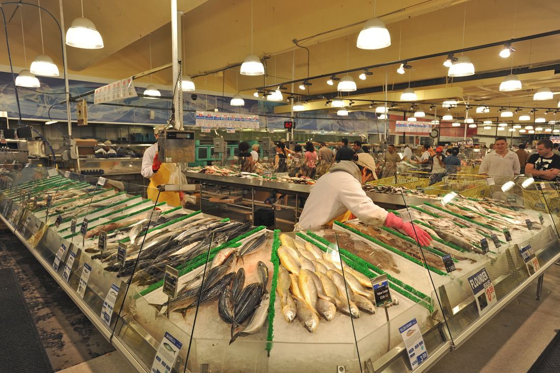 Workers arranging whole fish on ice at the Buford Highway Farmers Market seafood counter
