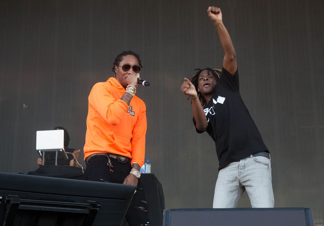 Future performing on an outdoor festival stage in an orange hoodie