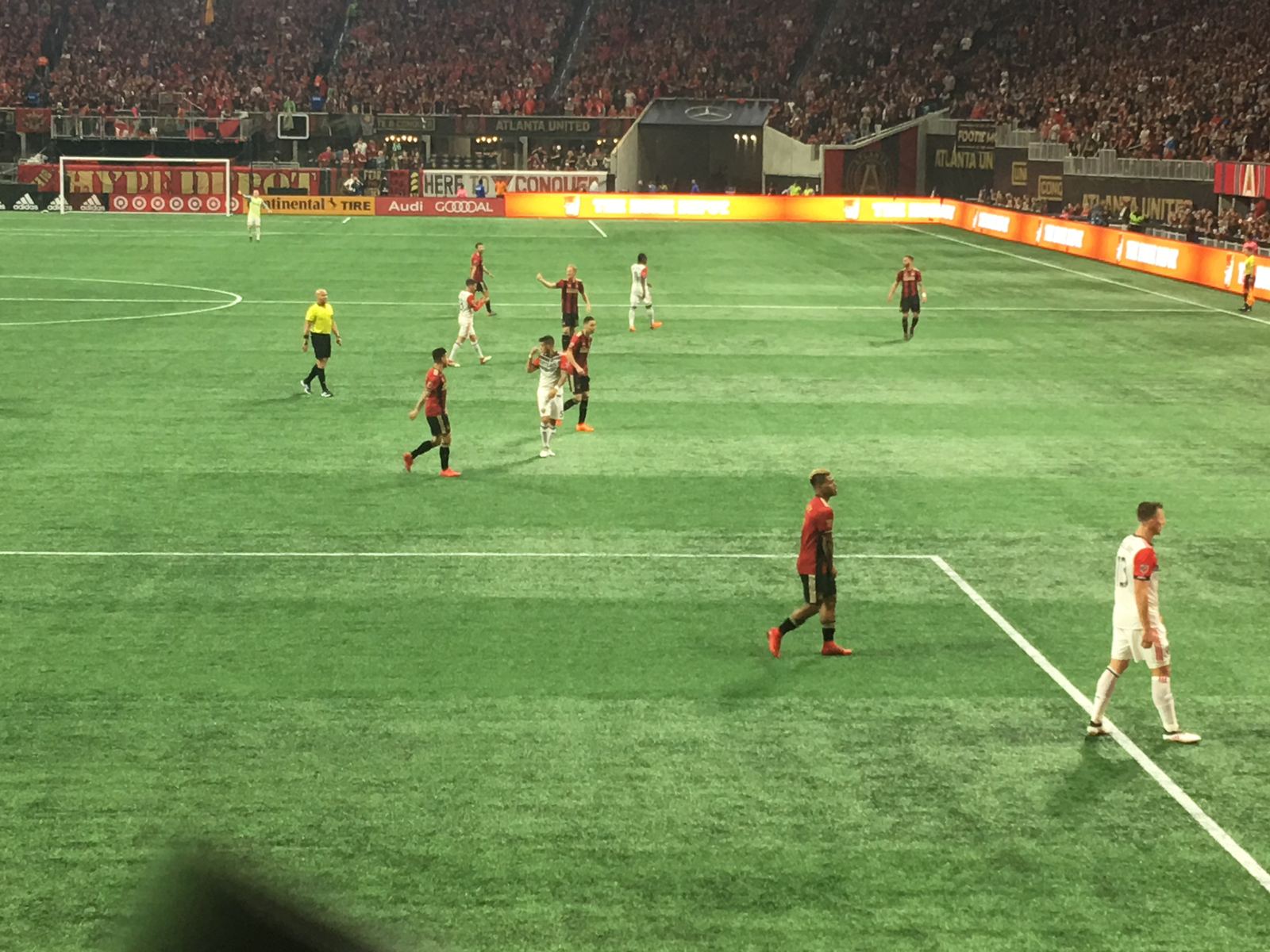Atlanta United players in red and black stripes on the pitch at Mercedes-Benz Stadium during a 2018 match