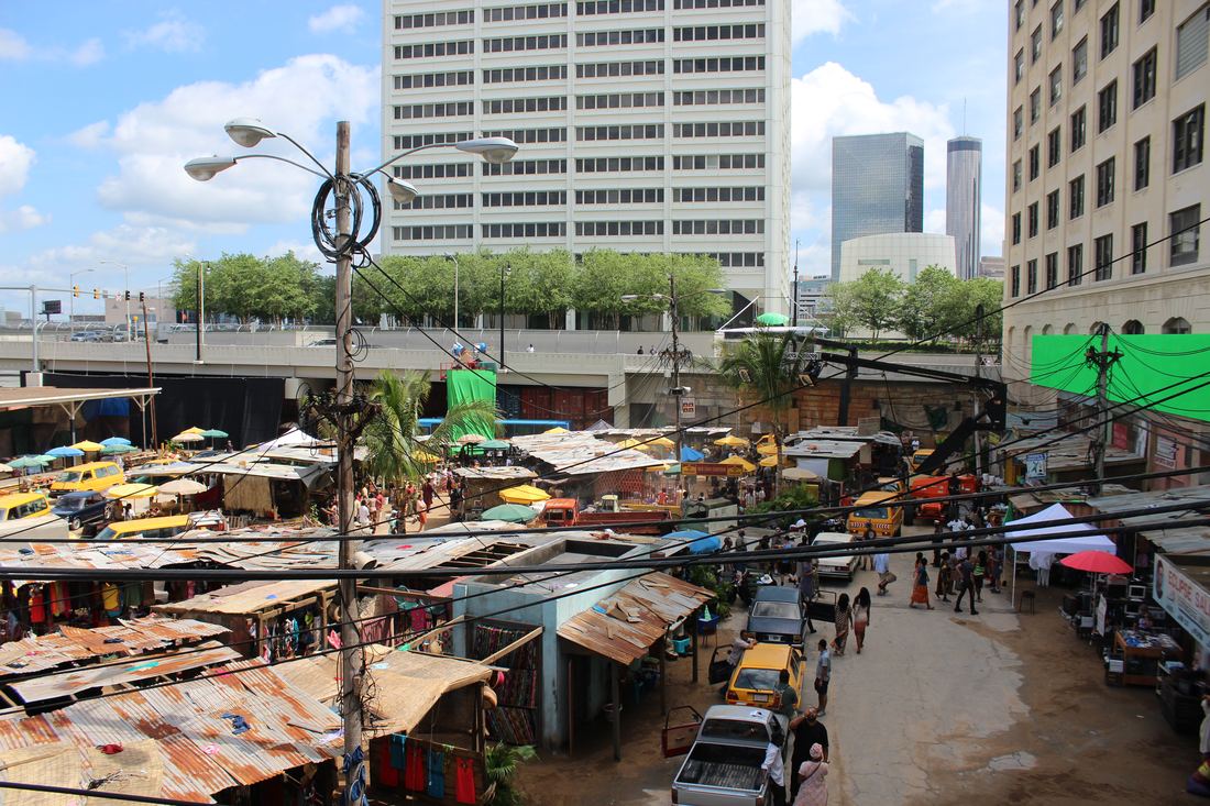 An Atlanta street dressed as a busy open-air market for a movie shoot, with tall buildings behind