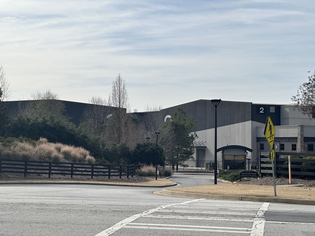 Gray soundstage buildings and a curving entrance road at Trilith Studios in Fayetteville, Georgia