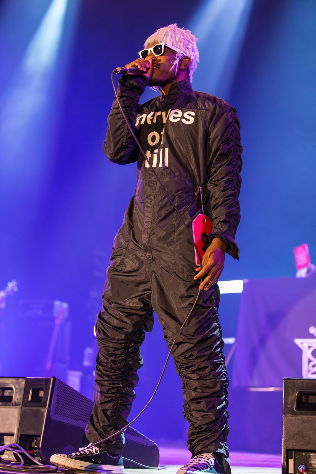 André 3000 in a black jumpsuit and white wig performing on stage